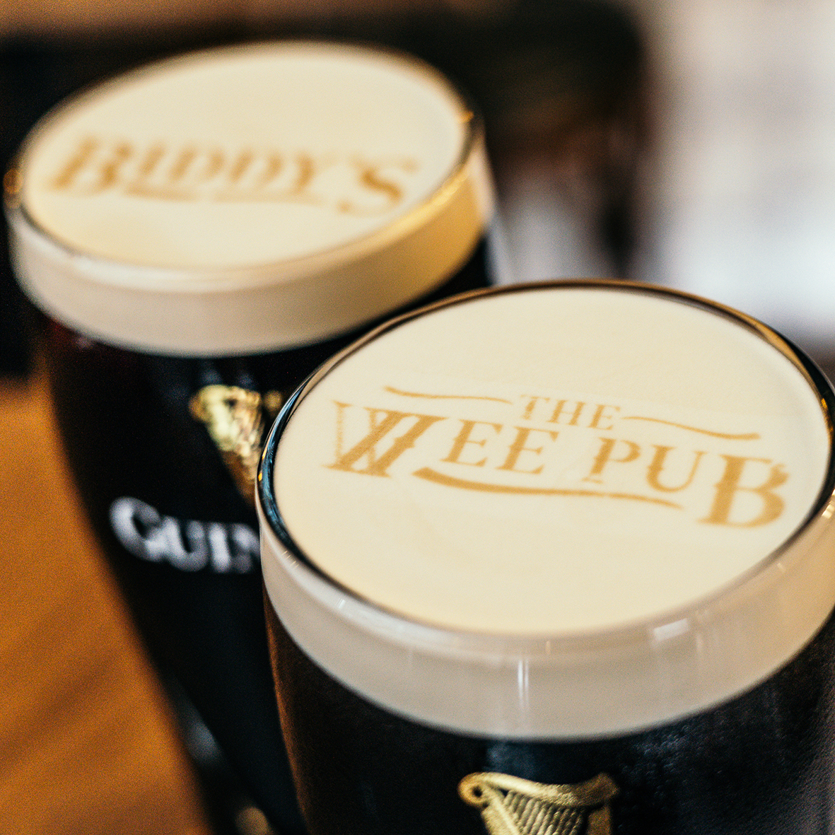 Close up shot of two pints of Guinness with our logos printed on the foam