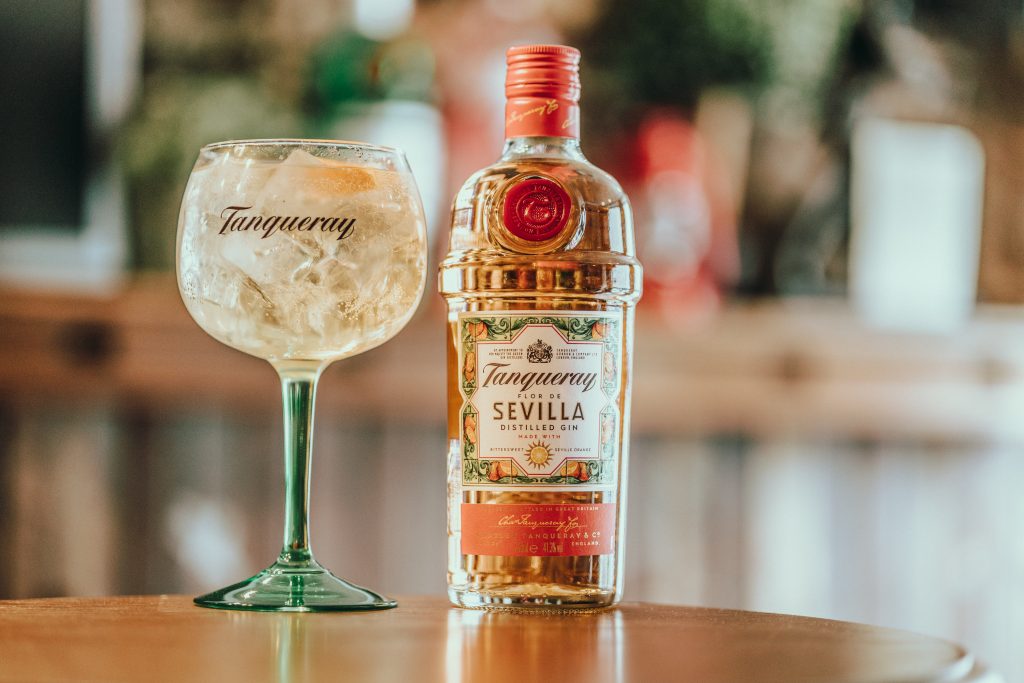 Tanqueray Sevilla gin bottle and a glass of mixed cocktail with ice